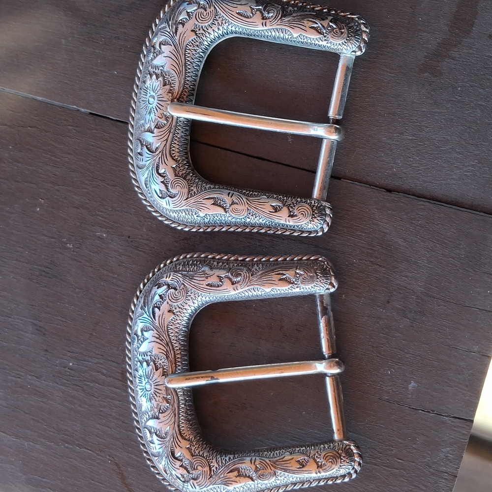 Two floral motif silver colored belt buckles
